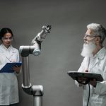 Dois cientistas trabalham com um braço robótico em um laboratório.