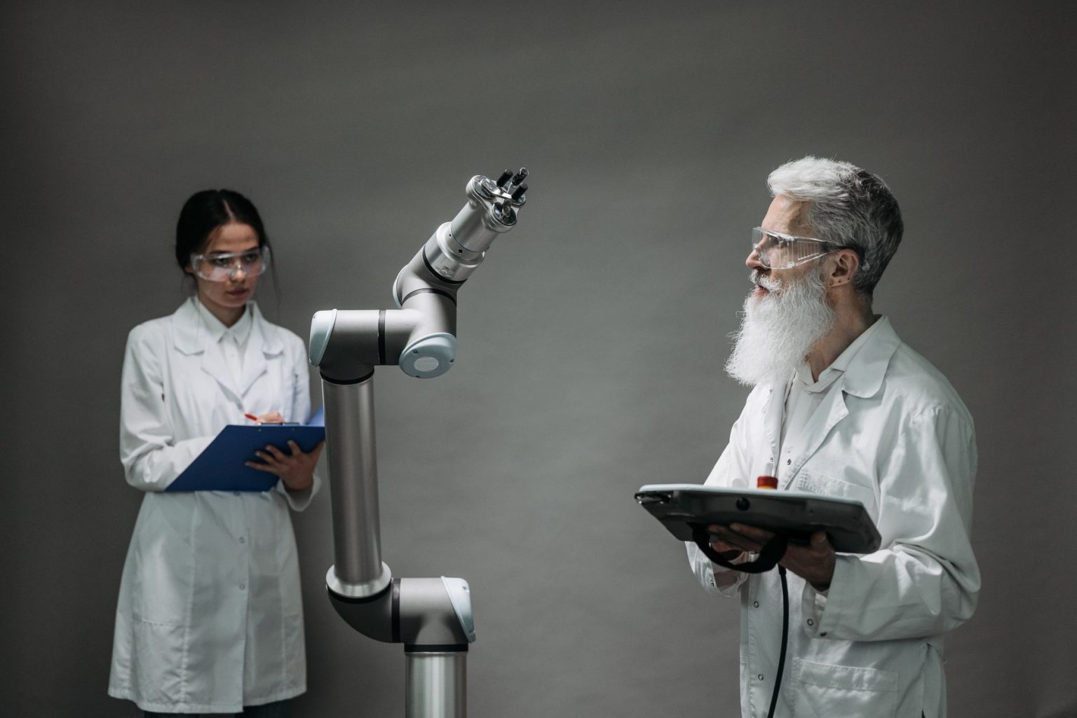 Dois cientistas trabalham com um braço robótico em um laboratório.