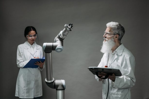 Dois cientistas trabalham com um braço robótico em um laboratório.