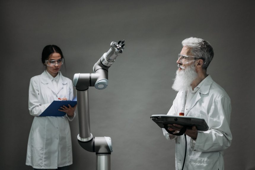 Dois cientistas trabalham com um braço robótico em um laboratório.
