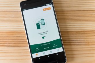 Smartphone exibindo uma interface de detecção de contatos sobre uma mesa de madeira