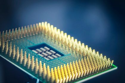 Imagem em close de um chip de computador com contatos dourados sobre fundo azul.