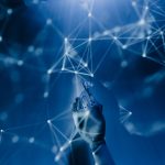 Mão robótica alcança uma rede digital iluminada sobre fundo azul, representando inteligência artificial e conectividade.