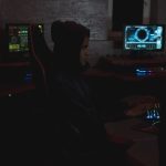 Profissional analisa dados em vários monitores em uma sala escura de operações de cibersegurança