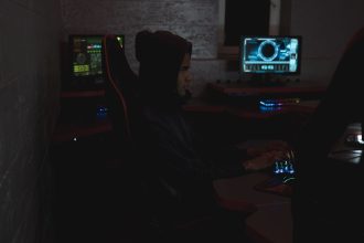 Profissional analisa dados em vários monitores em uma sala escura de operações de cibersegurança