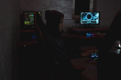 Profissional analisa dados em vários monitores em uma sala escura de operações de cibersegurança